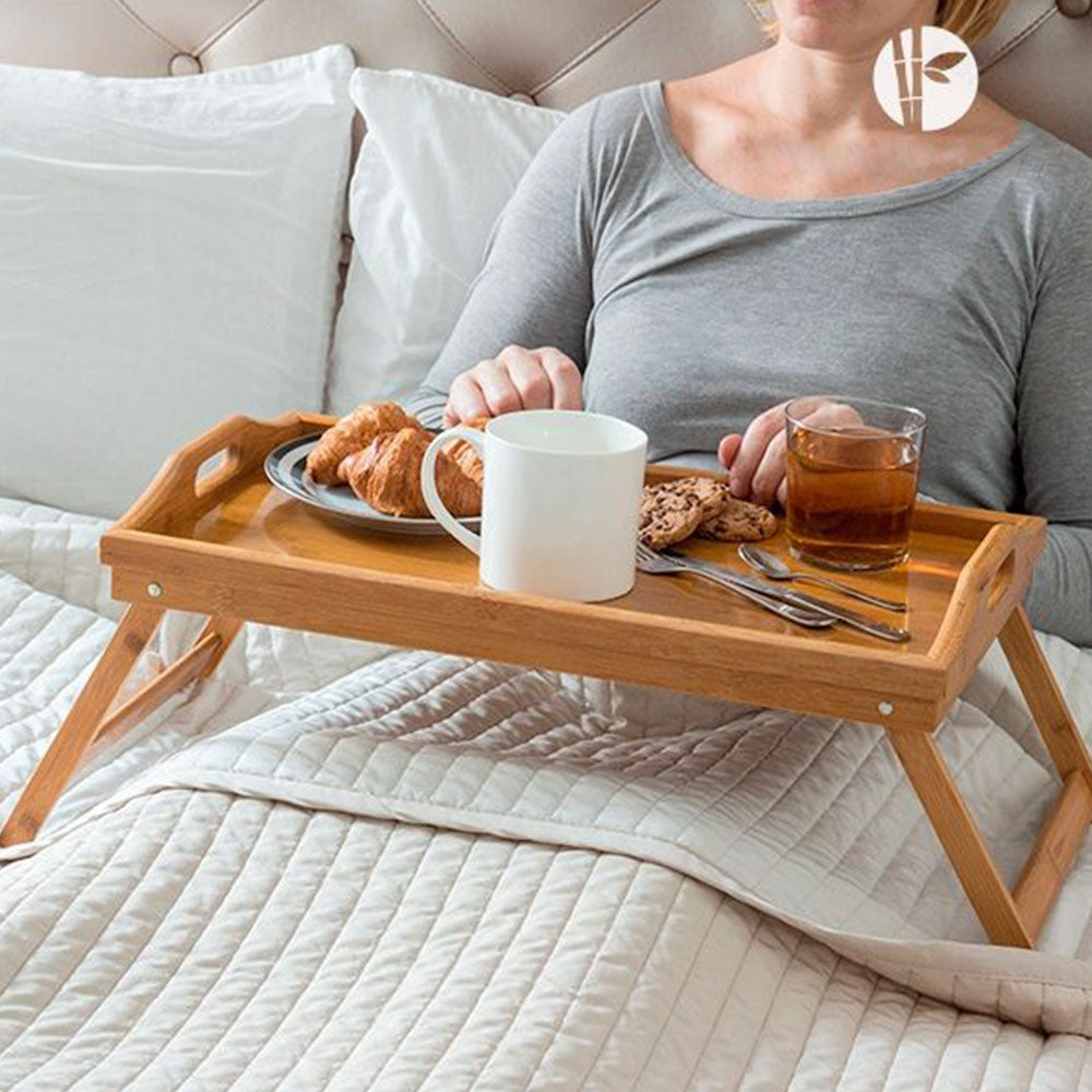 Bags Direct Eco-Friendly Bamboo Bed Serving Tray with Stand - 784200240 - showcasing its use by serving someone in bed. The fold out legs provide support and stability when you're lying in bed and eating